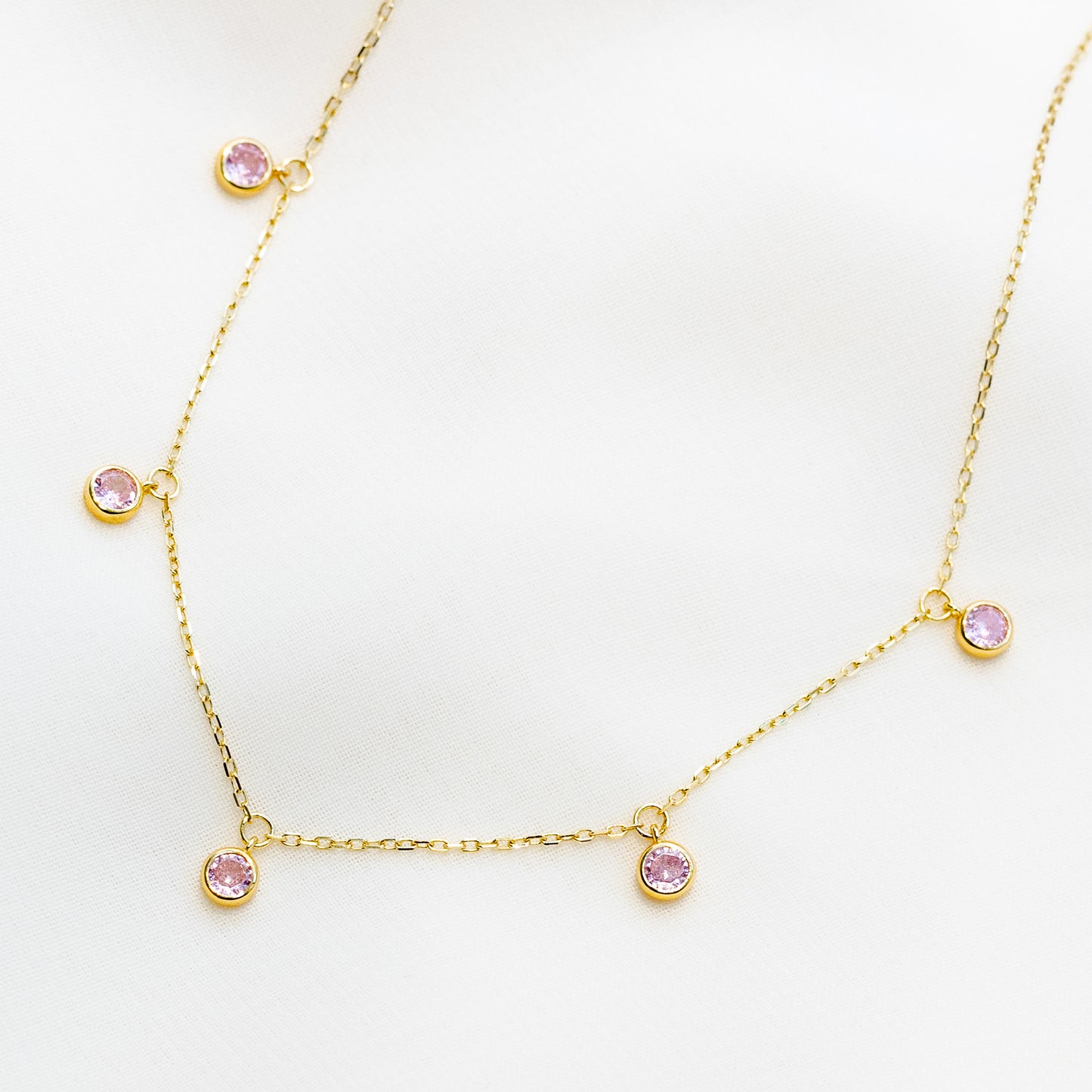 Minimalist 14k gold plated sterling silver station necklace featuring five light pink cubic zirconia bezel drops.