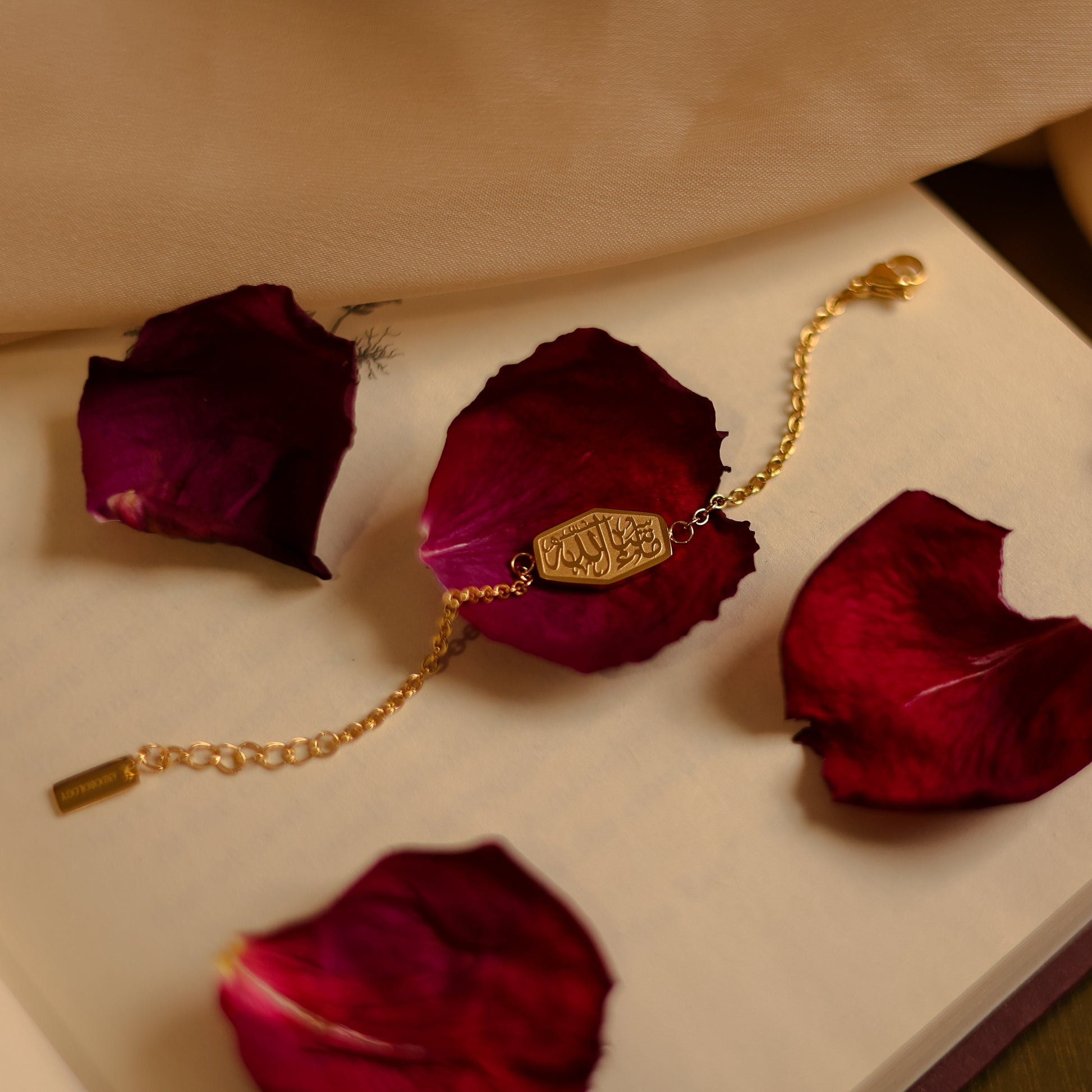 18k gold plated MashAllah bracelet displayed on red rose petals with elegant faith-inspired Islamic jewelry design.